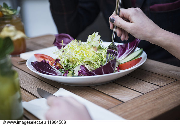 Cropped image of woman holding fork and eating salad
