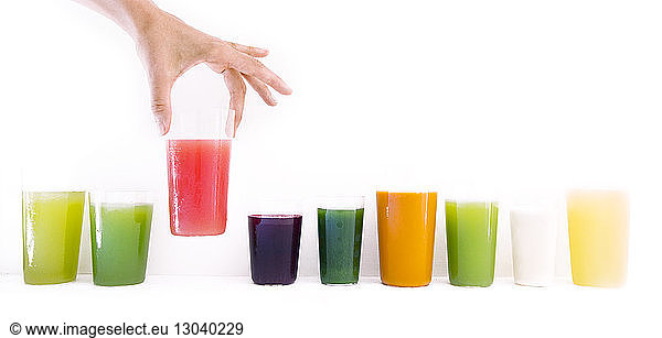 Cropped image of woman holding fresh juice glass against white wall