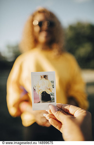 Cropped image of woman holding photograph against woman