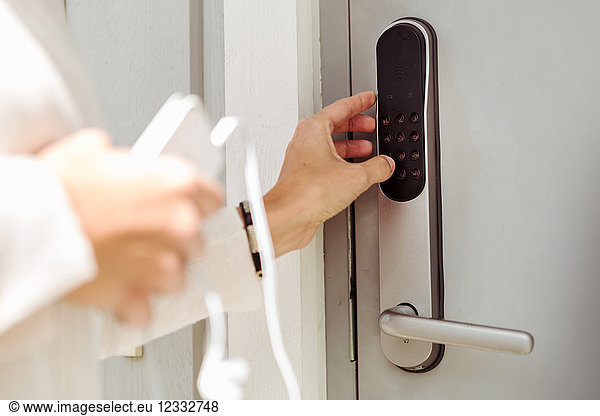 Cropped image of woman opening electric lock on silver door