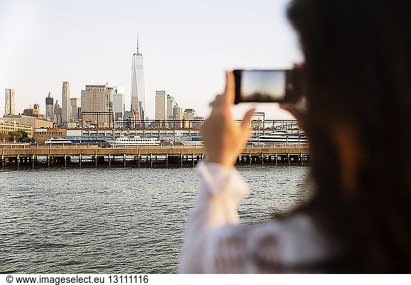 Cropped image of woman photographing skyline during sunset
