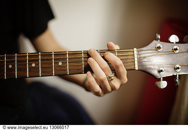 Cropped image of woman playing guitar at home