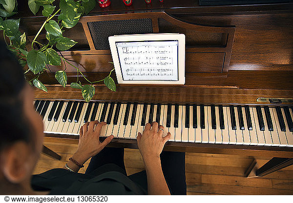Cropped image of woman playing piano at home