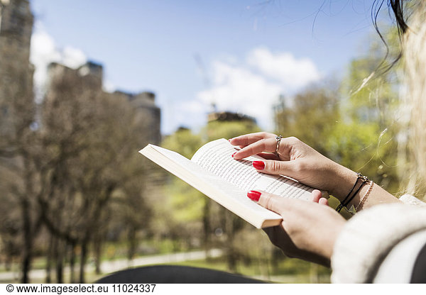 Cropped image of woman reading book at Central Park