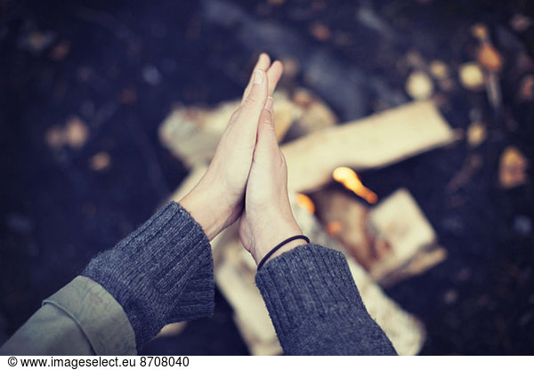 Cropped image of woman rubbing hands over campfire