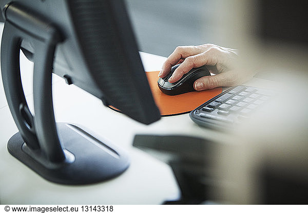 Cropped image of woman using computer at office desk