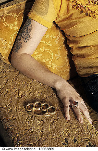 Cropped image of woman with brass knuckle sitting on sofa