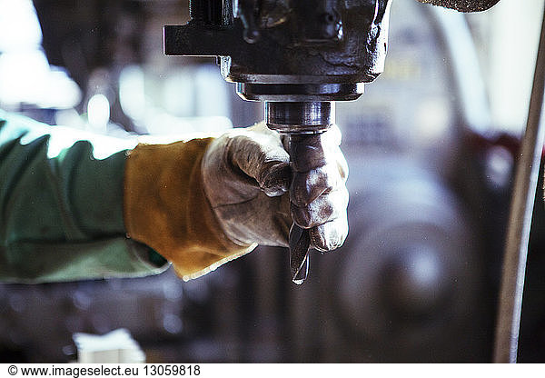 Cropped image of worker adjusting drill in workshop