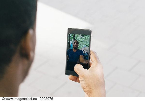 Cropped image of young man taking selfie from smart phone