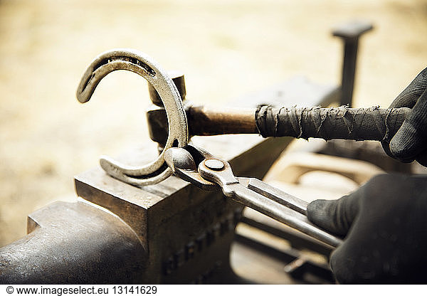 Cropped of farrier making horseshoe on anvil
