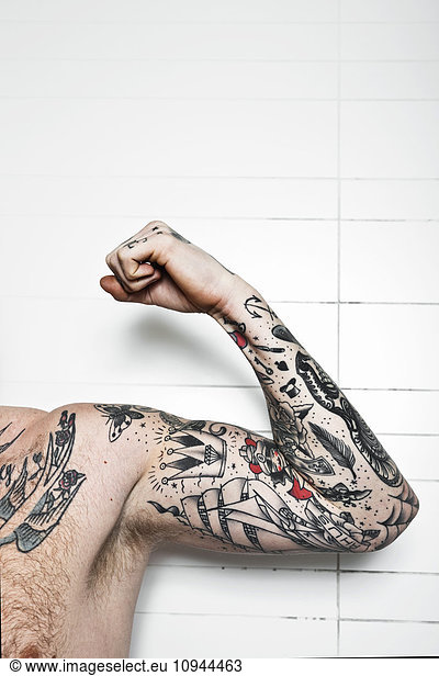 Cropped shot of a tattooed man flexing bicep