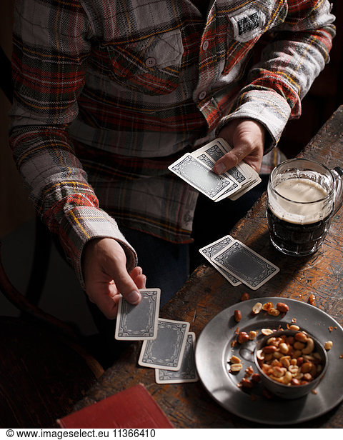 Cropped shot of man playing cards at pub table