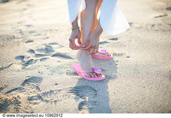 Cropped shot of woman fastening anklet on Santa Monica beach  Cresent City  California  USA