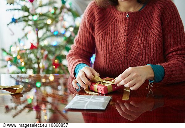Cropped shot of woman wrapping xmas gift at table