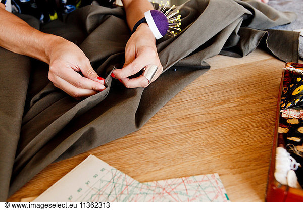 Cropped view of seamstress pinning fabric