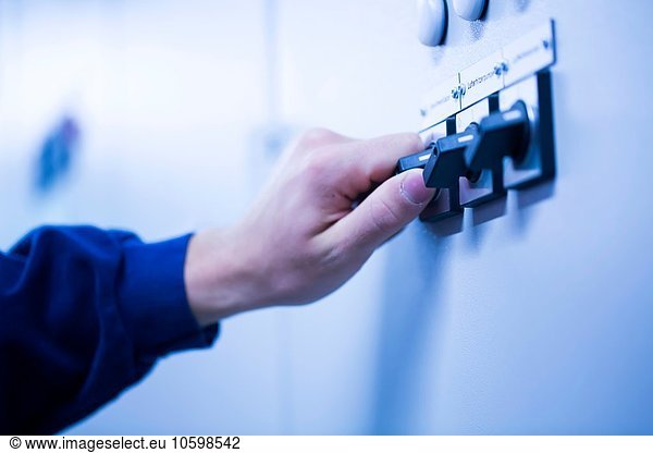 Cropped view of young mans hand adjusting dial on switchgear