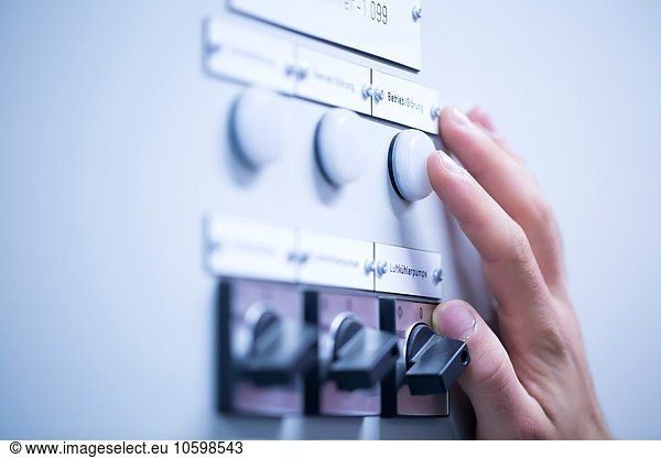 Cropped view of young mans hand adjusting dial on switchgear