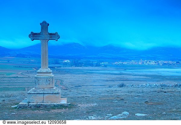 Cross of the hermitage and the village of Gallocanta on background at dusk. Wildlife reserve Laguna de Gallocanta.