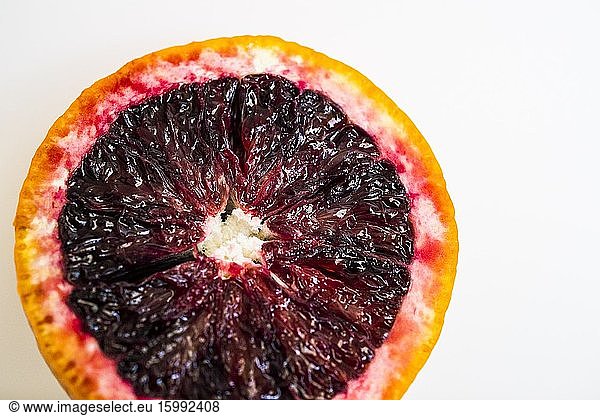 Cross section of a blood orange (Citrus sinensis) against a white background. Macro image.
