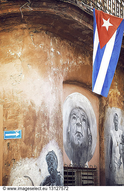 Cuban flag hanging from building with painting on wall