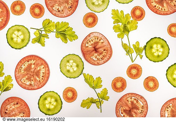 Cucumber  carrot and tomato in slices with parsley  white background  food photography
