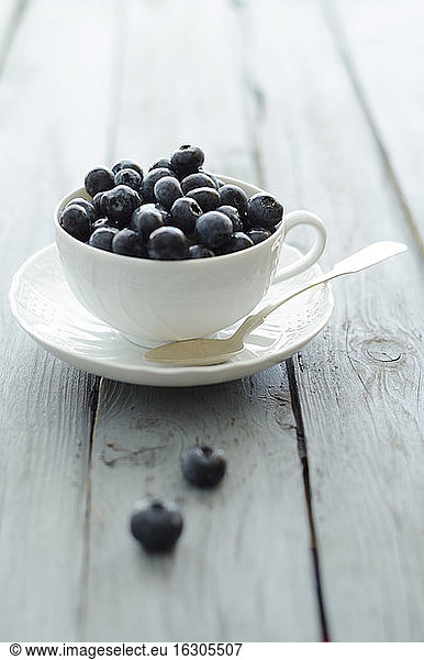 Cup of blueberries on wooden table  close up