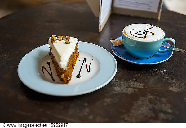 Cup of Cappuchino and piece of cake on table in a coffee shop