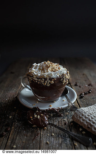 Cup of chocolate pudding with cream topped with nuts