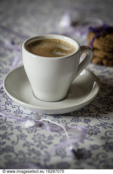 Cup of coffee and chocolate cookies on patterned cloth