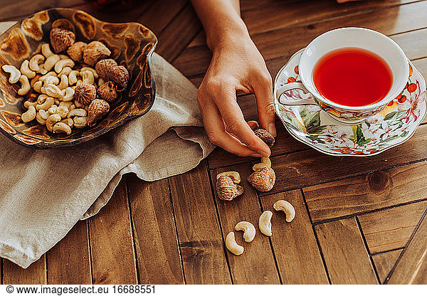 Cup of hibiscus tea  hand and dry fruits on top of a table