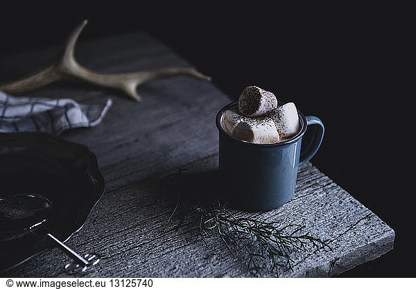 Cup of hot chocolate topped with marshmallow on wooden table