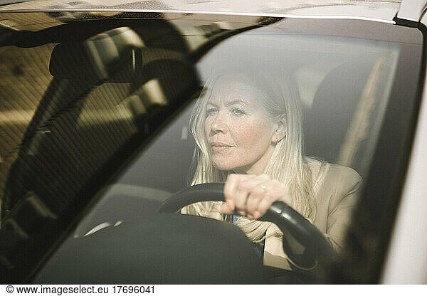 Curious businesswoman driving car seen through windshield