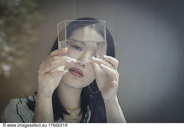 Curious female designer looking at cube with water