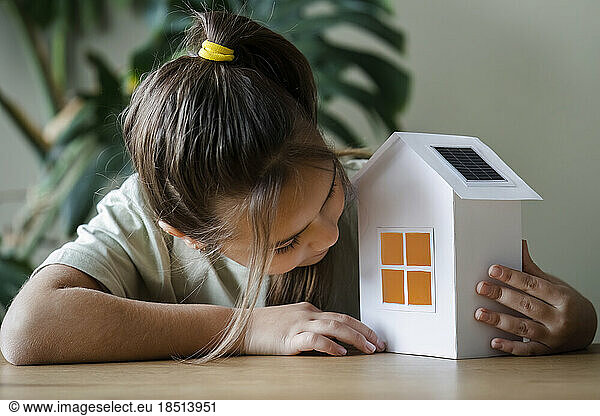 Curious girl looking inside house model on table
