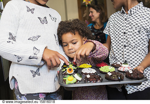Curious girl with decorated Halloween cupcakes