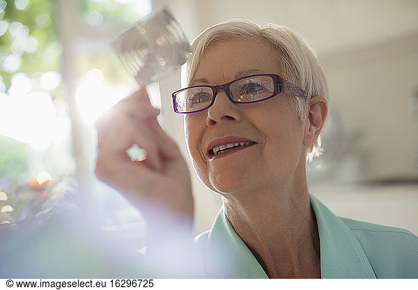 Curious senior woman examining cube in sunlight