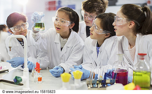 Curious students conducting scientific experiment  examining liquid in beaker in laboratory classroom