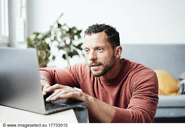 Curious working man using laptop at home office
