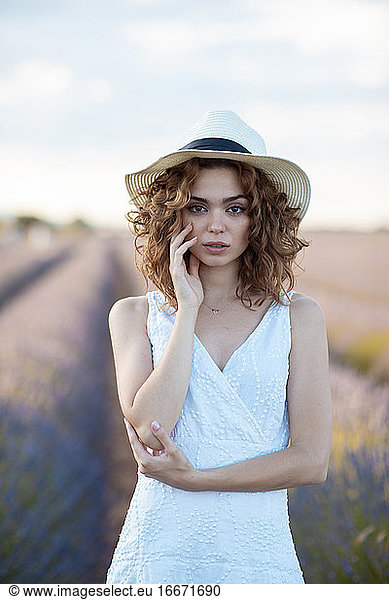 curly-haired woman with a hat outdoors