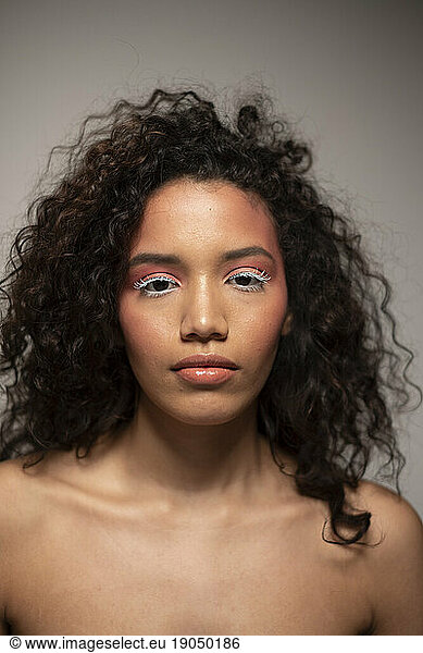 Curly woman headshot posing nude with Coral Makeup