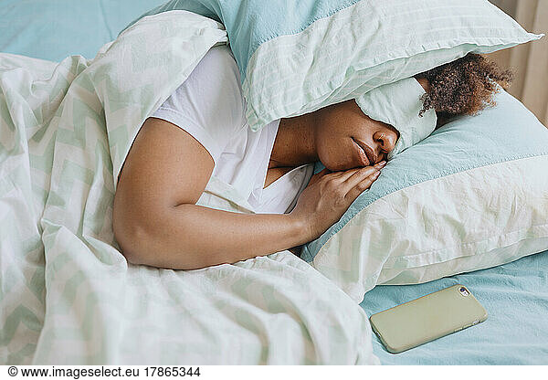 Curly woman sleeping with sleep mask on her face.