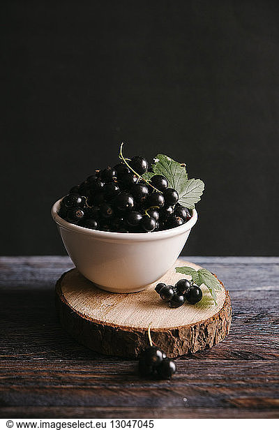 Currants in bowl on table against black background
