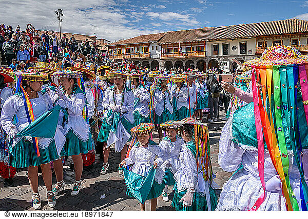 Cusco  a cultural fiesta  people dressed in traditional colourful costumes with masks and hats  brightly coloured streamers.