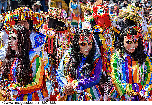 Cusco  a cultural fiesta  people dressed in traditional colourful costumes with masks and hats  brightly coloured streamers.