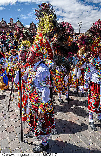 Cusco  a cultural fiesta  people dressed in traditional colourful costumes with masks and hats with feathers.