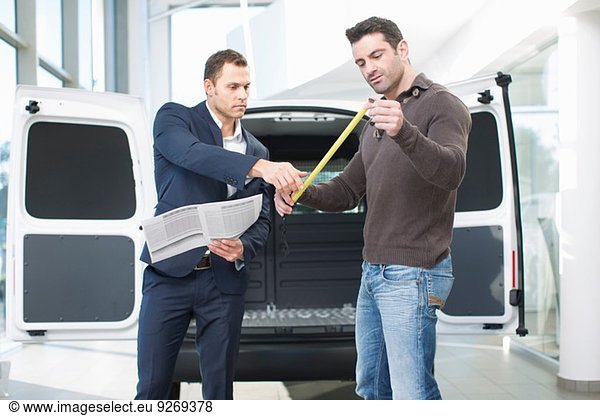 Customer and salesman checking van measurements in car dealership