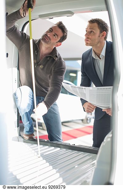 Customer and salesman checking vehicle interior height in car dealership