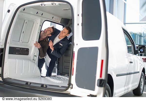 Customer and salesman checking vehicle interior in car dealership