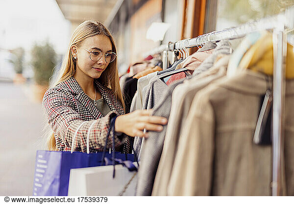Customer choosing clothes hanging on rack outside store