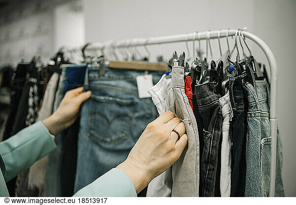 Customer choosing jeans from rack in store